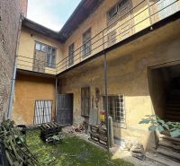 A courtyard of commercial spaces with worn plaster and plants in Šahy on the Main Square.