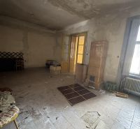 Abandoned commercial spaces with a tiled stove and large French doors.