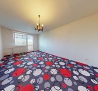 A living room with a colorful carpet and a chandelier in a three-room apartment.