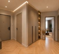 The entrance hall of a three-room apartment with a wooden decor floor and stylish lighting.