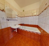 A bathroom in a 3-room apartment with a bathtub, sink, and tiles in warm tones.