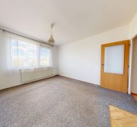 A room in a 3-room apartment with a carpet, white walls, and wooden doors.