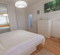 A bedroom in a 3-room apartment with white furniture and a floor with a wood decor.