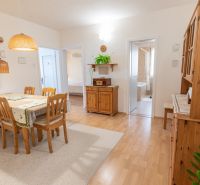 A bright dining room in a 3-room apartment with wooden furniture and a wood-patterned floor.
