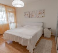 Bright bedroom with a large bed, wood-patterned floor, lamp, and curtains.