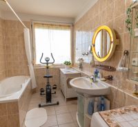 A bathroom with a bathtub, exercise machine, and mirror in a 3-room apartment.