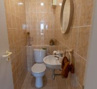 Bathroom in a 3-room apartment with a mirror, sink, and toilet in beige tiles.
