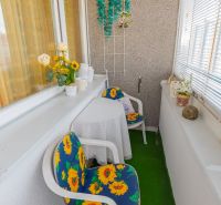 A balcony of a 3-room apartment with chairs and sunflowers, cozily furnished for relaxation.
