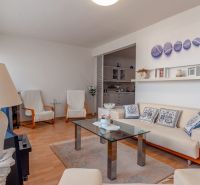 Living room with a sofa, glass table, and wooden decor flooring in a three-room apartment.