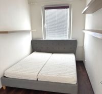 A bedroom in a 3-room apartment with a comfortable bed and shelves, wooden decor flooring.