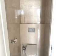 A toilet with a wooden decor floor in a 3-room apartment.