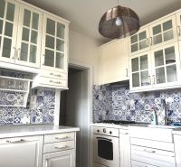 A kitchen unit with glass cabinets and blue-white tiles in a 3-room apartment.