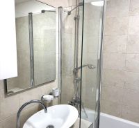 Bathroom in a 3-room apartment with a bathtub and a sink, light tiles on the walls.