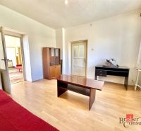 Living room in a family house with a wooden decor floor and simple furnishings.
