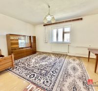 A room in a family house with a carpet, a chair, a wardrobe, and a bed.