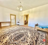 A family house with a large carpet, wooden table, and simple furniture.