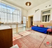 Interior of a family house with a sofa, carpet, and a large window with lace curtains.