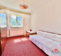 A room in a family house with a red carpet, a sofa, and a wardrobe.