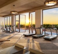 Fitness center with a view of the sunset, equipped with cardio machines and strength training equipment.