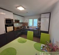 A kitchen in a family house with green chairs and built-in appliances.