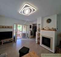 Living room in a family house with a fireplace, television, and wooden decor flooring.