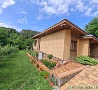 A family house in Veľké Uherce surrounded by a green garden and trees.