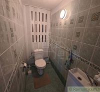 A bathroom in a family house with a toilet, tiled with a patterned design.