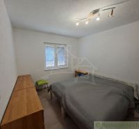Bedroom in a family house with a bed, cabinet, and ceiling lamps.