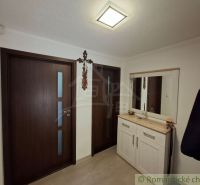 The family house has an entrance hall with white furniture, a mirror, and wooden doors.