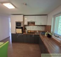 A kitchen in a family house with corner cabinets, white appliances, and a view from the window.