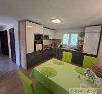 A kitchen in a family house with white cabinets and a table with colorful chairs.