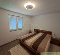 Bedroom with a double bed, nightstands, and a wooden decor floor in a family house.