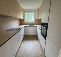 A kitchen with white cabinets and a wood-patterned floor in a 3-room apartment.