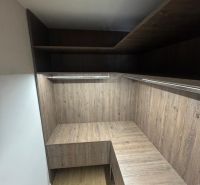A wardrobe in a 3-room apartment with shelves and a wooden decor floor.
