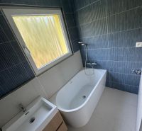Bathroom in a 3-room apartment with a bathtub, sink, and dark walls.