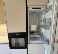 A kitchen in a 3-room apartment with a built-in refrigerator and oven, floor with wooden decor.