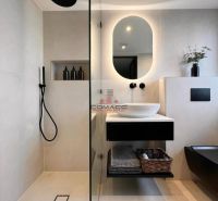 A bathroom in a family house with a sink, shower, basket, and mirror.