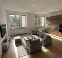 A bright living room space with a sofa, dining table, and wood-decor flooring in a three-room apartment.