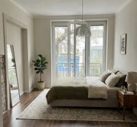 A bedroom in a 3-room apartment with large windows and a wooden decor floor.