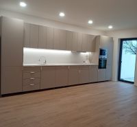 A kitchen in a family house with a wooden decor floor and built-in appliances.