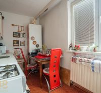 A kitchen in a family house with a table and red chairs, decorations on the wall.