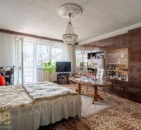 A bedroom in a family house with a bed, a living room wall unit, and a chandelier.