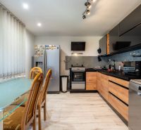 A kitchen in a family house with a wooden decor floor and a dining table.
