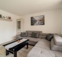 Living room in a family house with a gray sofa, pictures, and a floor with a wooden decor.