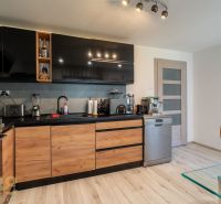A kitchen in a family house with black cabinets, wooden decor, and appliances.