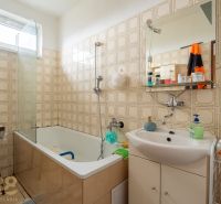 A bathroom in a family house with a bathtub, a sink, and retro tiles.