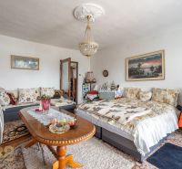 Living room in a family house with a sofa, table, chandelier, and decorative pillows.