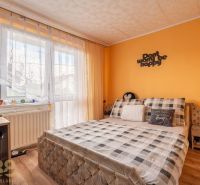 A bedroom in a family house with a bed, a desk, and a floor with a wooden decor.