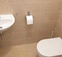 Bathroom with toilet, sink, and beige tiles in a studio apartment.
