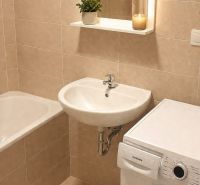 Bathroom with a bathtub, sink, mirror, and washing machine in a studio apartment.